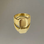 A gold-colored signet ring with engraved detailing and a polished finish.