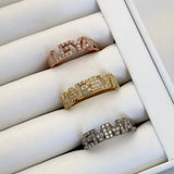 A set of silver rings with varying designs, displayed in a box, with one ring featuring a custom stone word inscription.