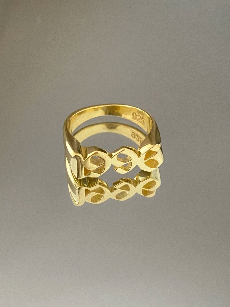 A gold-colored metal ring with a geometric pattern, featuring the inscription '925' on the inside.