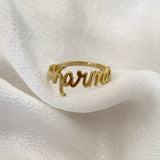A gold-colored custom ring with the name 'Karma' written on it, displayed on a white fabric surface.